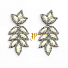 A pair of silver and white leaf-shaped earrings with a gold-colored inscription.